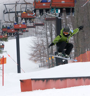 Kid jumping off a rail in a terrain park.